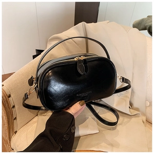 Close-up of black oil-wax leather small square bag with golden hardware and leather strap