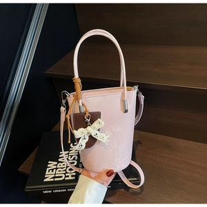 Detail of pink bucket bag with pearl finish PU leather, handles and lace bow charm