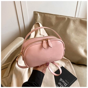 Pink oil wax leather handbag with double zipper and detachable strap in a lifestyle setting
