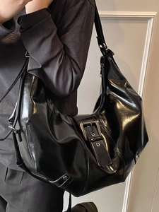 Vintage black patent leather hobo tote bag with silver buckle worn by a model