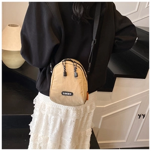 Detail of light brown nylon crossbody bag featuring Lucky patch and black adjustable strap