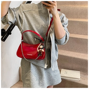 Glossy red patent leather half-moon bag featuring a cute boy doll and pearl charm