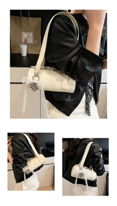 Macro shot of a cream-white cylindrical shoulder bag with lace bow and heart charm details