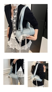 Detail of light blue cylinder shoulder bag with lace bow and silver heart charm pendant