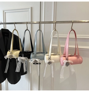 Detail of five colorful barrel bags with lace bows and heart charms on a metal rack