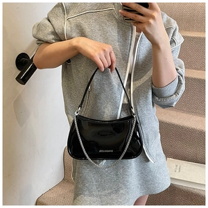 Detail of black patent leather shoulder bag with silver chain and white logo lettering