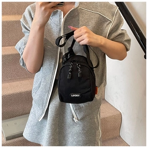 Detail view of casual black nylon crossbody bag with LUCKY patch and orange side label