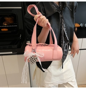 Detailed view of pink barrel bag with white lace bow and silver heart pendant