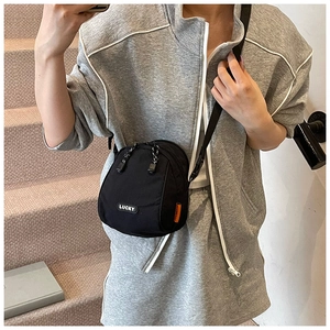 Close-up of a black casual crossbody bag with Lucky patch and adjustable strap