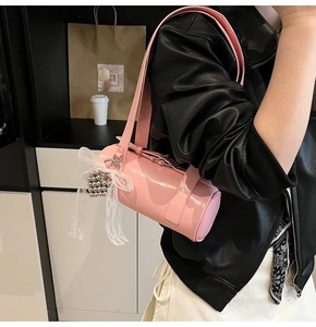 Detail of pink glossy cylinder bag featuring lace bow and silver bead pendant accessories