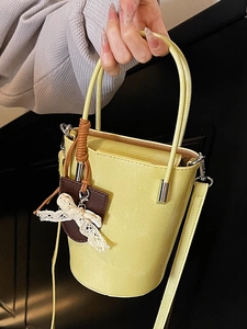 Pale yellow leather bucket bag with lace bow pendant and versatile shoulder strap