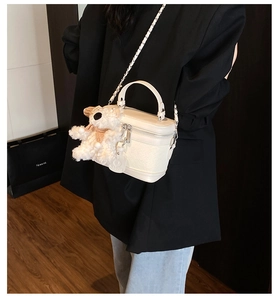 White woven crossbody box bag with silver chain strap and a cute teddy bear pendant