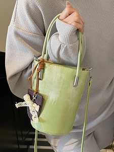 Minimalist avocado green bucket bag with white brush texture and lace bow detail