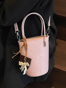 Pink cylinder bucket bag in faux leather with a lace bow and detachable shoulder strap