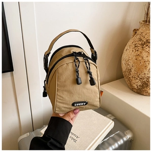 Macro shot of khaki nylon mini bag with LUCKY label and woven zipper pullers