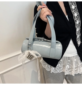 Detail view of glossy light blue baguette bag with a decorative lace bow charm