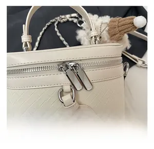 Detailed view of woven texture box bag with metallic double zipper and chain strap