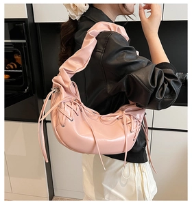 Détail du sac à bandoulière rose avec bandoulière froncée et lacets décoratifs sur le côté