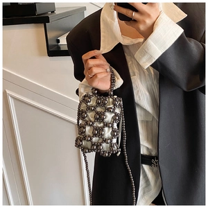 Detail der grau gewebten Perltasche mit weißem Satinfutter und feinem Kettenriemen