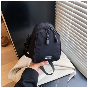 Detail of black nylon mini crossbody bag with double zippers and Lucky rubber patch