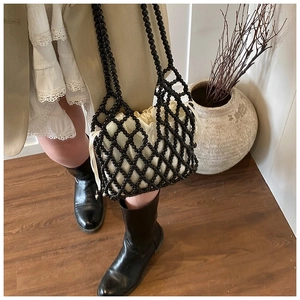 Détail d'un sac à main en perles noires tissé à la main avec doublure en satin crème et filet
