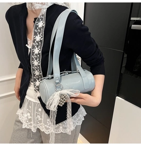 Macro shot of light blue cylindrical baguette bag with lace bow and silver bead detail