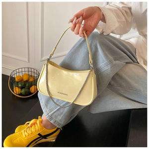 Detail of creamy yellow patent leather shoulder bag with silver chain and BAFANSHA logo