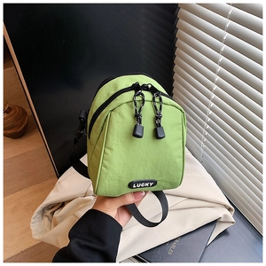 Detail shot of a green mini crossbody bag with LUCKY rubber logo and zipper texture