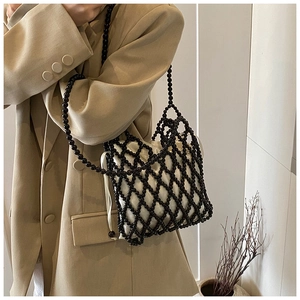 Détail d'un sac perlé tissé à la main avec structure en filet noir et pochette en satin blanc