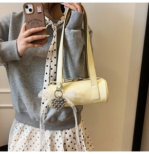 Detail of light yellow barrel bag with white lace bow and heart beaded pendant
