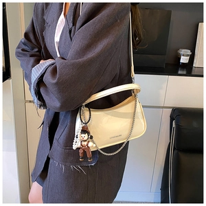 Detail view of glossy patent leather shoulder bag with chic silver chain and charm