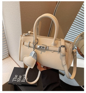 Detailed view of beige lychee leather handbag with silver twist lock and heart charm
