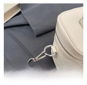 Detailed macro of woven cream leather bag featuring silver metal clasp and sturdy chain strap