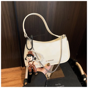 Detail of cream patent leather half-moon bag with silver chains and pearl charms