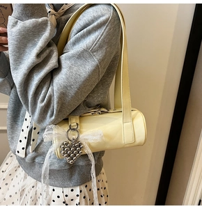 Detail of cream baguette bag with lace bow and silver heart beaded charm detail