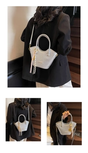 Détail du sac seau argenté tressé avec pompon décoratif et pendentif doré élégant