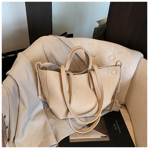 Minimalist beige lychee grain leather bucket bag on an armchair in a lifestyle setting