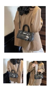 Detail of black lychee grain leather handbag with silver lock and heart charm accessory
