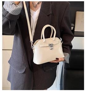 Detailed side view of cream-colored oil wax leather shell bag worn by model
