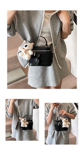Detail of black box-shaped crossbody bag with a cute white teddy bear plush charm