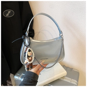 Detail of silver patent leather baguette bag with pearl doll charm and chain strap