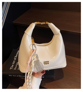 Detailed view of white glossy leather half-moon bag with golden buckle and abacus pendant