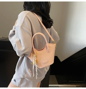 Sac seau rose à texture tissée avec foulard rayé, porté en bandoulière par un mannequin
