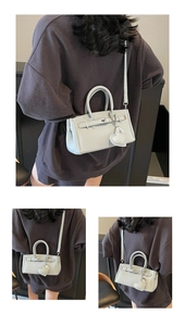 Detail view of mini lychee texture handbag with metal turn-lock and heart charm
