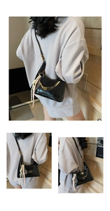 Detail of black glossy leather bag featuring golden letters and braided tassel charm