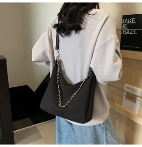 Minimalistische schwarze Tragetasche aus Kunstleder mit silberner Kette am Model