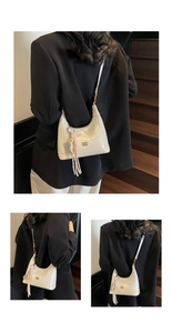 Detail of white patent leather hobo bag with gold metal letters on a wooden staircase