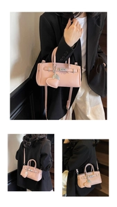 Detail of pink lychee leather handbag featuring silver hardware and heart charm attachment