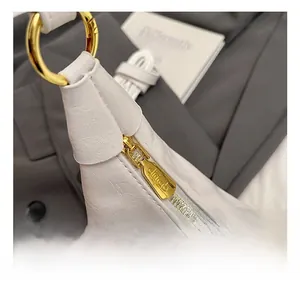 Macro shot of smooth gold zipper and refined oil-wax leather texture on cream tote bag