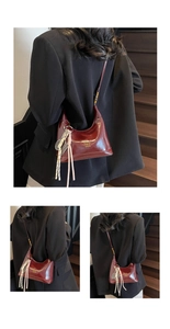 Detail of burgundy glossy oil wax leather hobo bag with gold text and tassel pendant
